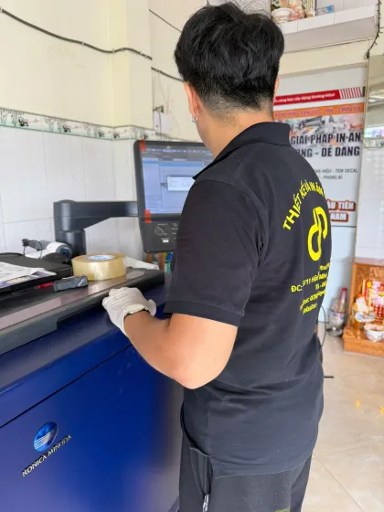 Kỹ thuật viên D&P thao tác trên máy in Konica Minolta — xưởng in gần vòng xoay Phú Lâm, Quận 6